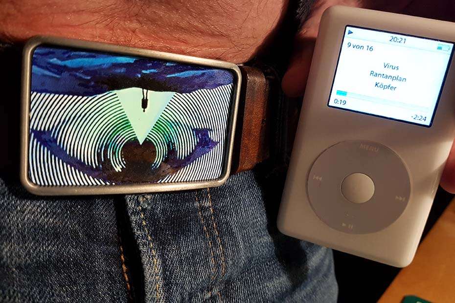 The beld buckle worn - where the design turns out to be upside down - and an old ipod is held next to it. The ipod is playing a song by Rantanplan