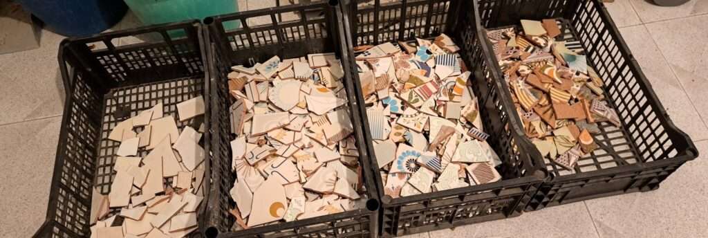 Four black vegetable boxes with tile pieces which are sorted by colour