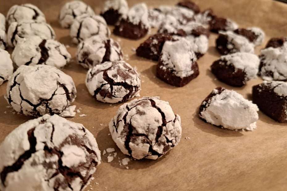 a baking tray of brown ball shaped cookies covered in powdered sugar